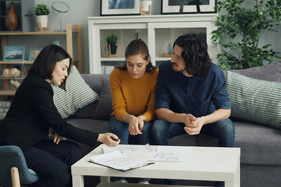 real estate agent sitting with clients and answering their real estate related questions