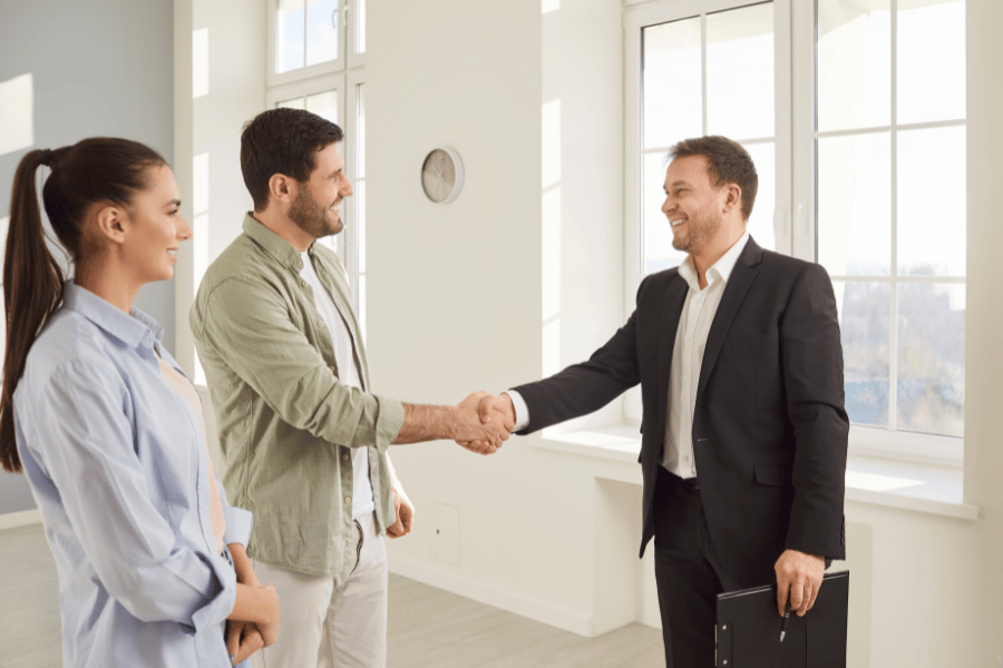 real estate agent shaking hands with potential homebuyers.