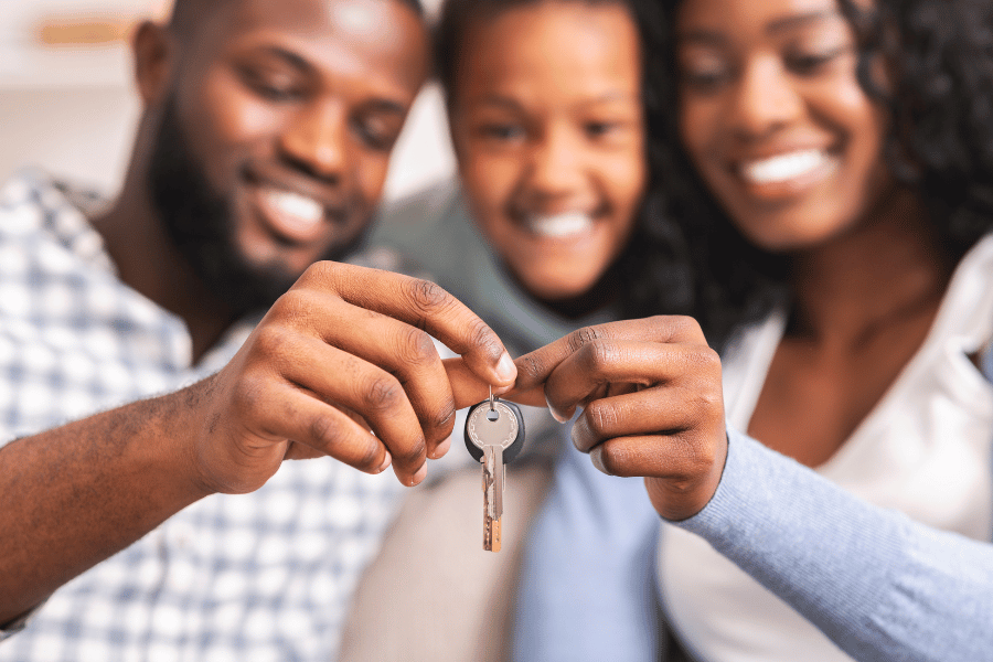 family of three holding the keys to their new home after being referred to an agent