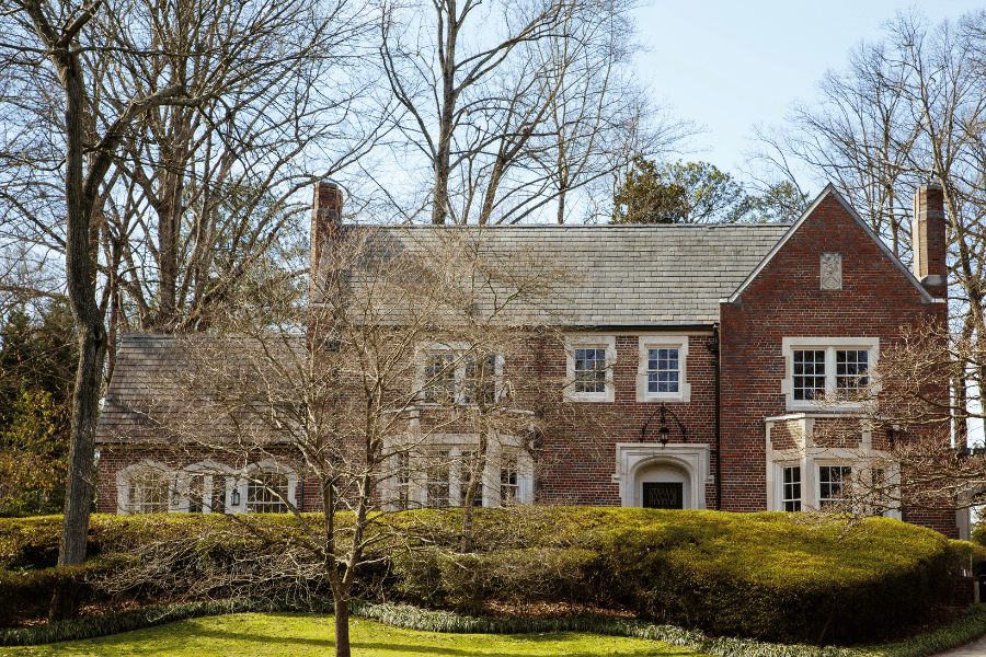 large brick luxury home with two chimneys and lots of windows