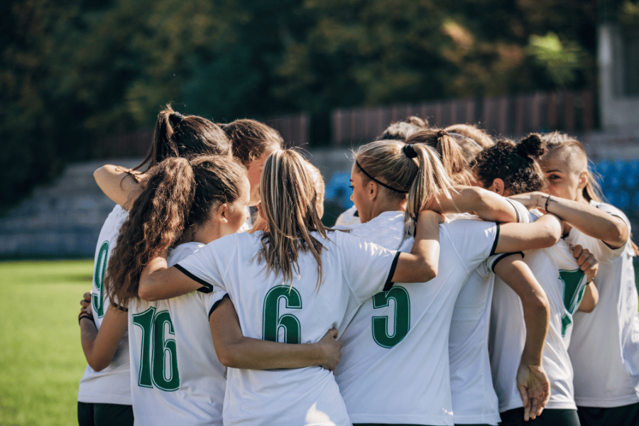 local sporting event girls soccer team in a huddle on the field